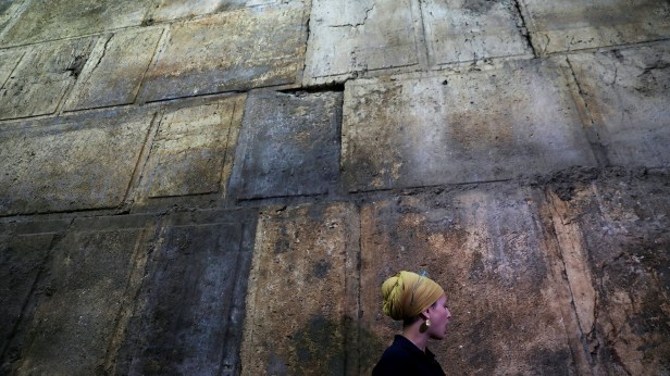 Israel Antiquities Authority archaeologist Tehillah Lieberman stands next to a part of the Western Wall, during a media tour revealing a theatre-like structure which was discovered during excavation works underneath Wilson's Arch, in Jerusalem's Old City